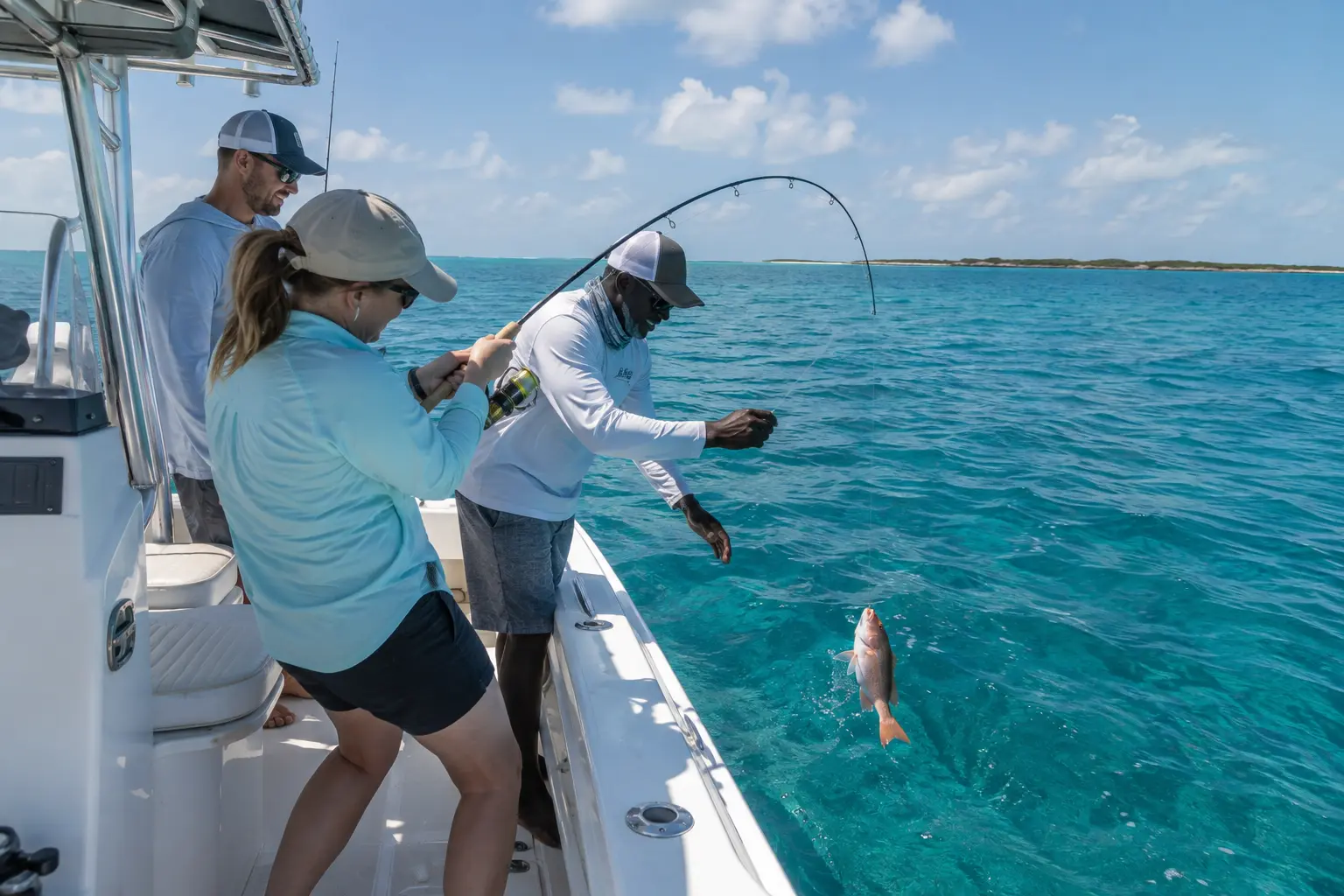 Guests and a local captain reef fishing from a center-console boat in Exuma